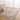 Patterned rug on a wooden floor with a chair and table in a room with white curtains.