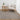 Living room with a gray rug, white armchair, wooden side table, and plant.