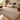 Caramel textured rug with a subtle bordered design and overlocked edges, styled in a modern living room with a cream sofa, wooden coffee table and timber flooring.