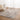 Gray area rug on a wooden floor with white curtains in the background