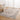 Patterned rug on a wooden floor with a chair and table in a room with white curtains.