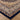 Close-up of a patterned rug with a blue border on a wooden floor.
