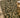 Decorative green and beige patterned rug with a wooden stool on the side.
