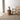 Wicker chair and side table with a plant on a light wooden floor.