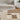 Patterned rug on a wooden floor with a beige sofa and plant in the background