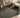 Living room with a olive green rug, beige armchair, wooden side table, and abstract art.