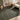 Living room with a olive green rug, beige armchair, wooden side table, and abstract art.