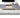 Gray area rug in a living room setting with a blurred TV and furniture.