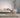 Modern living room with a beige sofa, wooden stool, and a plant in a white pot.
