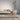 Modern living room with a beige sofa, wooden stool, and a plant in a white pot.