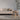 Modern living room with a beige sofa, wooden stool, and plant.
