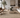 Modern living room with a beige sectional sofa, wooden chairs, and decorative elements.