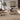 Modern living room with a beige sectional sofa, wooden chairs, and decorative elements.